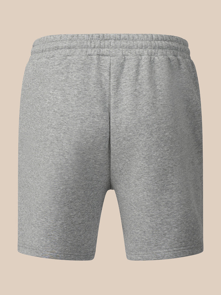 A pair of heather gray sweat shorts with an elastic waistband, shown from the back on a solid beige background.