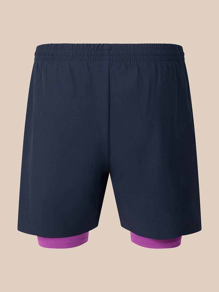 Dark navy athletic shorts with a built-in purple compression liner visible at the legs, shown against a solid beige background.