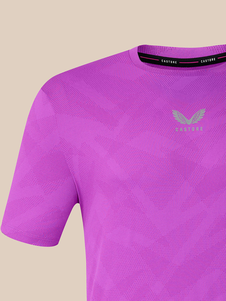 A close-up of a purple short-sleeve athletic t-shirt with a subtle geometric pattern, featuring a light gray winged logo and the brand name 'Castore' on the chest and inner collar.