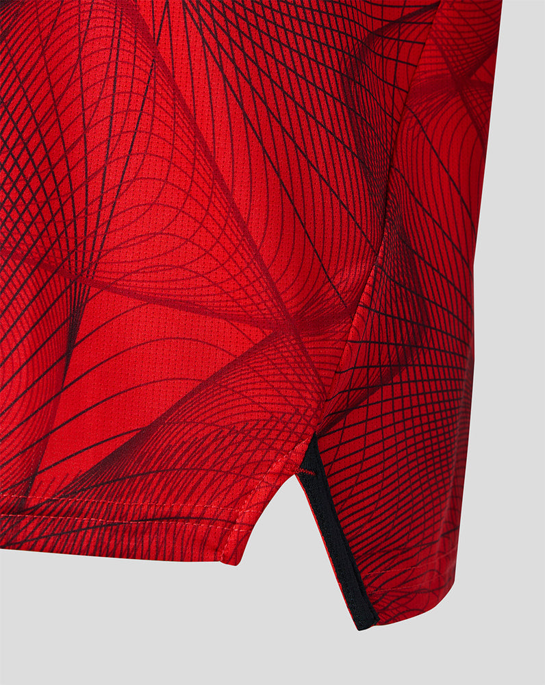 Lower side of the red matchday jersey showing the geometric pattern and a black hem trim with a small slit
